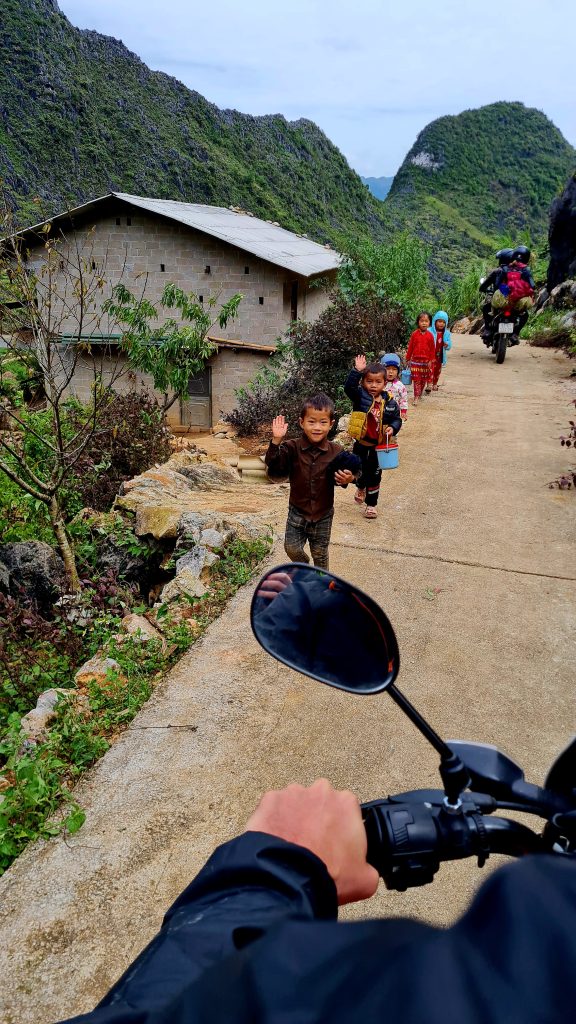 Kids saying hello while travelers are on a motorbike in Vietnam